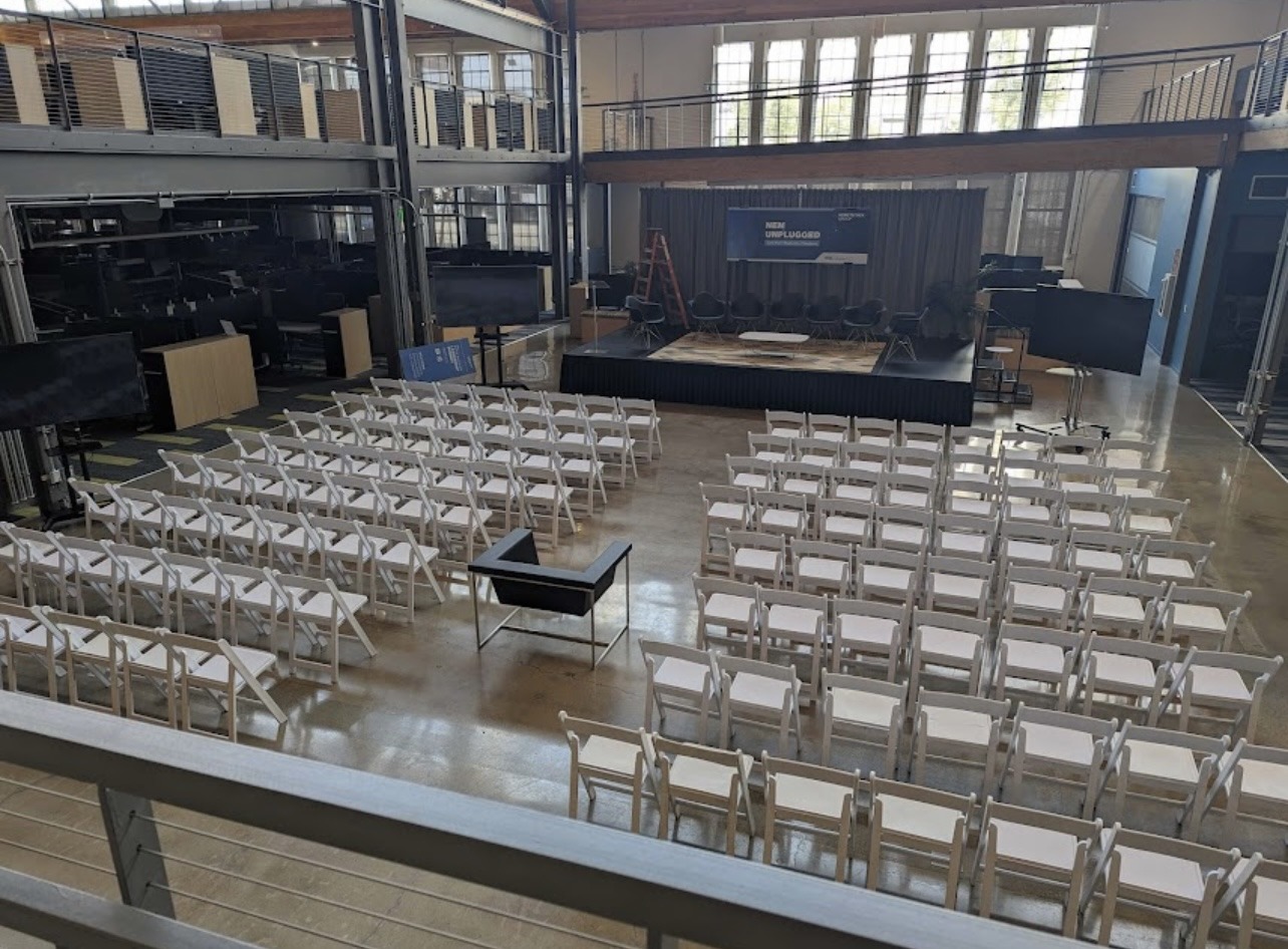Rows of white chairs facing an indoor presentation area