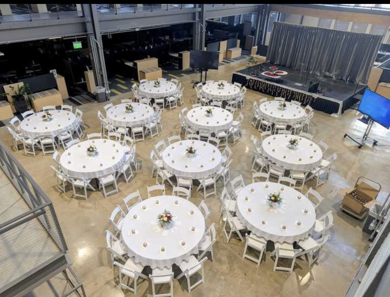 Round tables and white chairs arranged for an indoor banquet