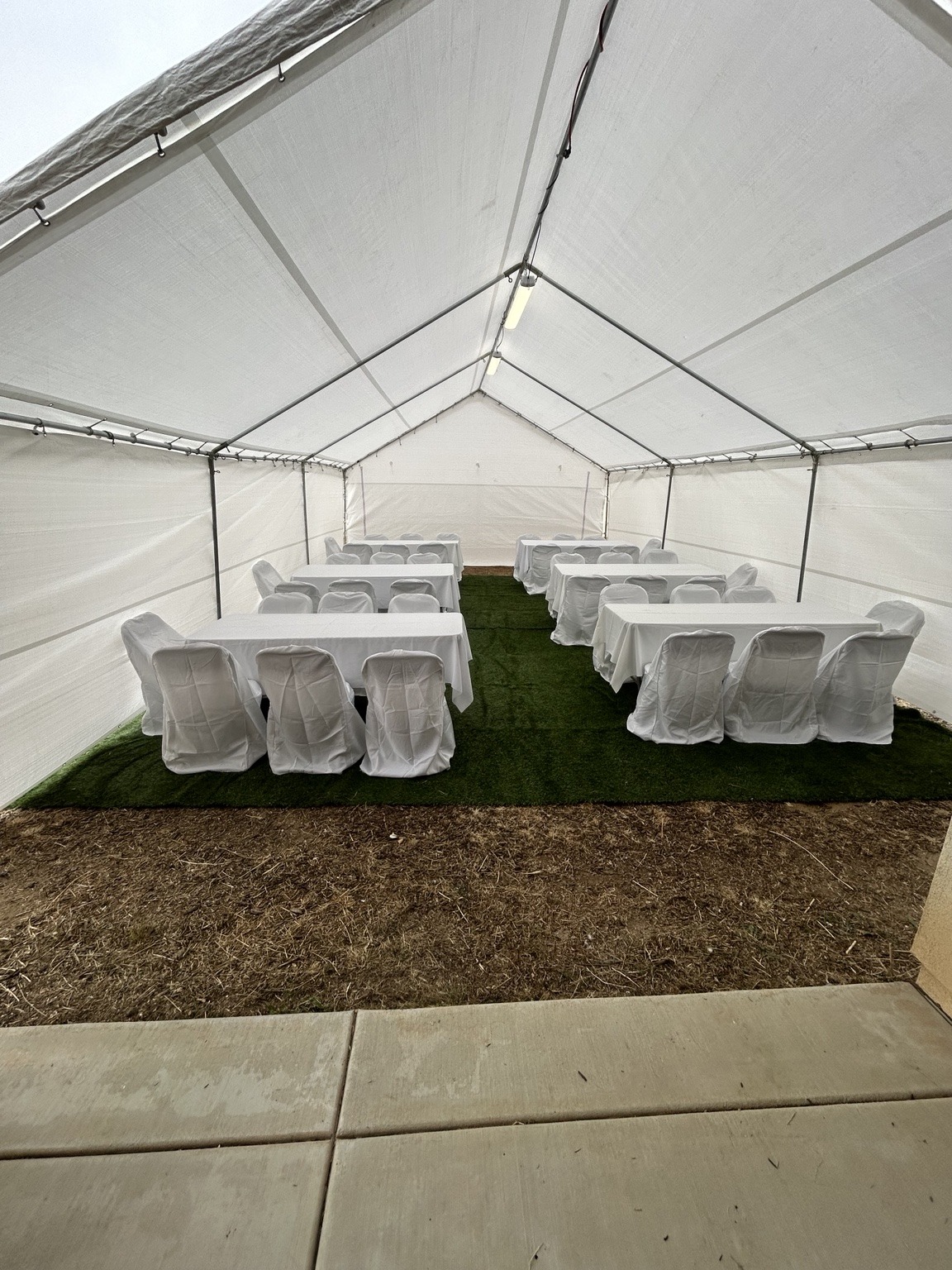 Regular white canopy furnished with rectangular tables, white linens, and covered chairs