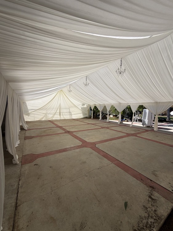 Ivory draping and chandelier detail in a real outdoor canopy setup
